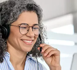 mulher falando por fone portátil e olhando computador