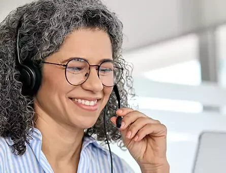 mulher falando por fone portátil e olhando computador
