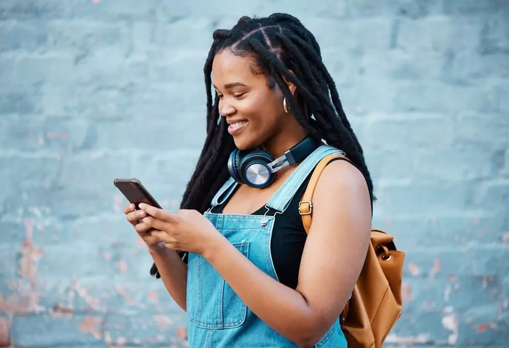 moça sorridente mexendo em celular