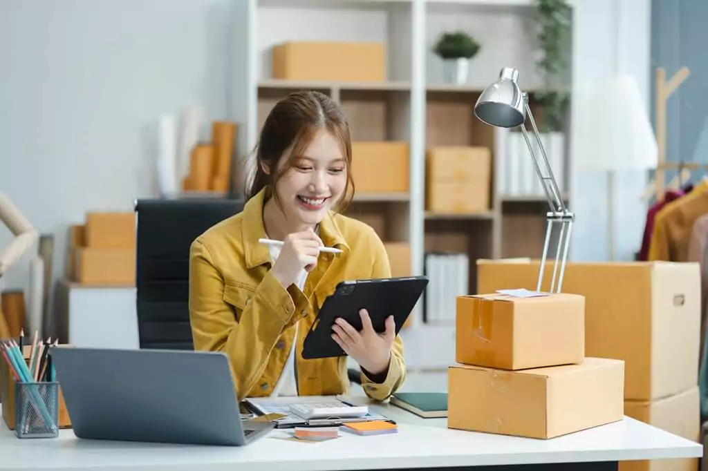 vendedora com tablet e caixas ao lado