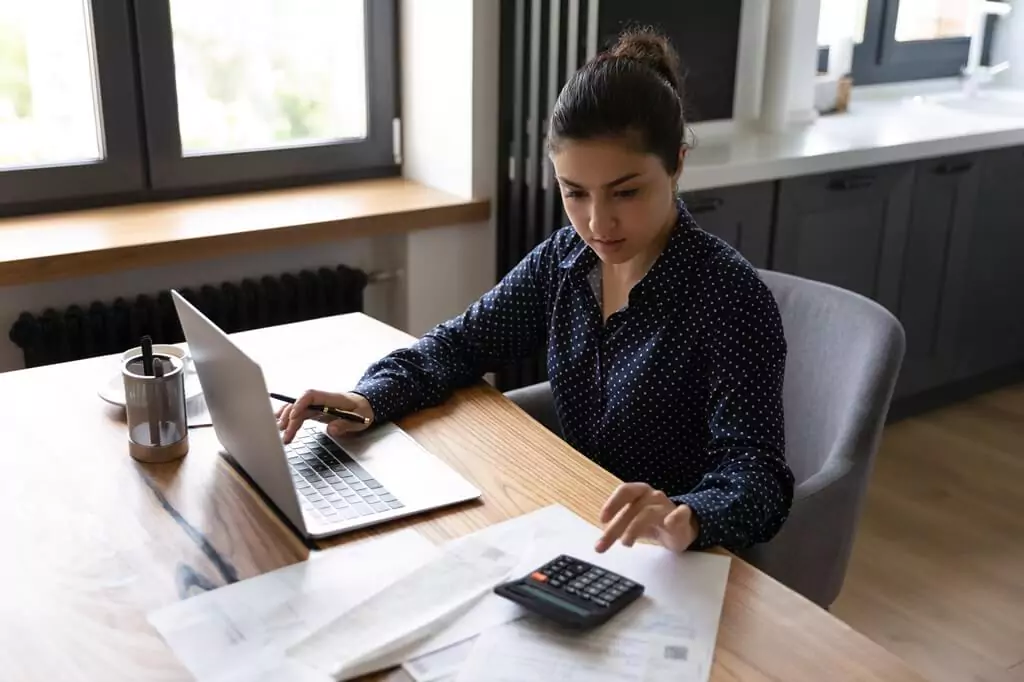 moça fazendo contas com calculadora e trabalhando com computador