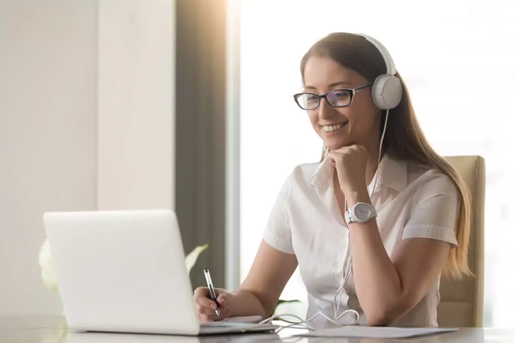 moça fazendo anotações e analisando algo em computador