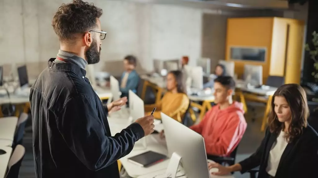 rapaz dando aula para pessoas mexendo em computador