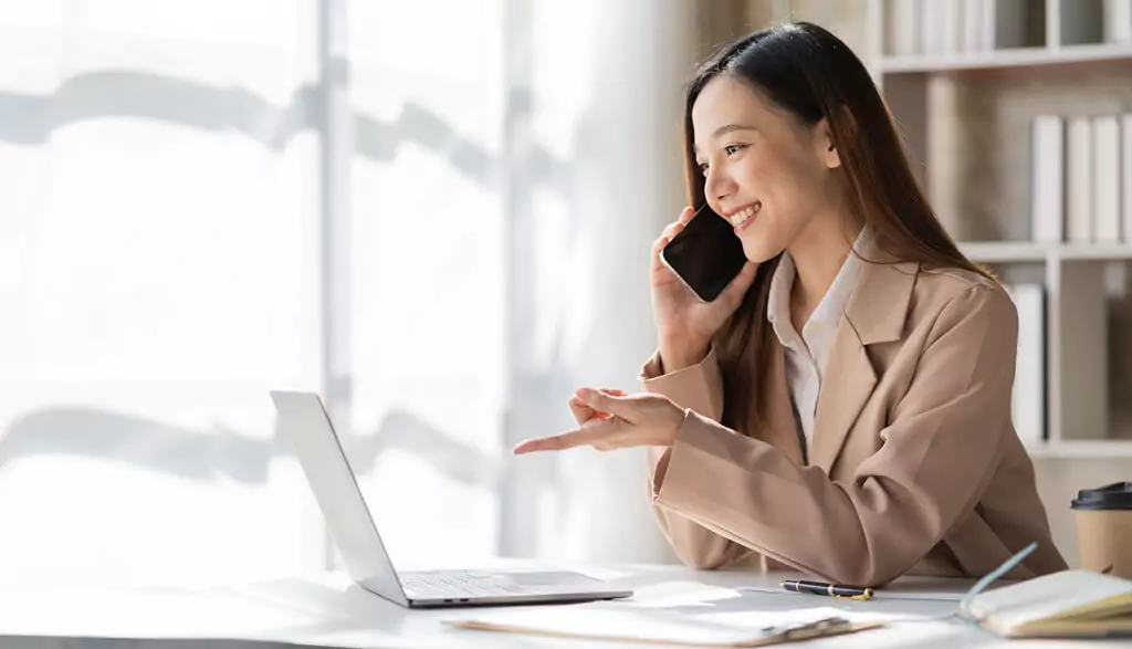 moça ao telefone apontando para computador
