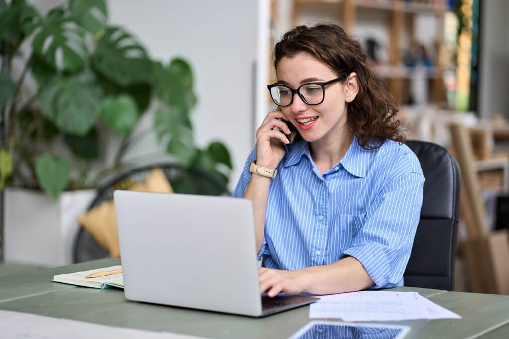 moça falando ao telefone e olhando computador